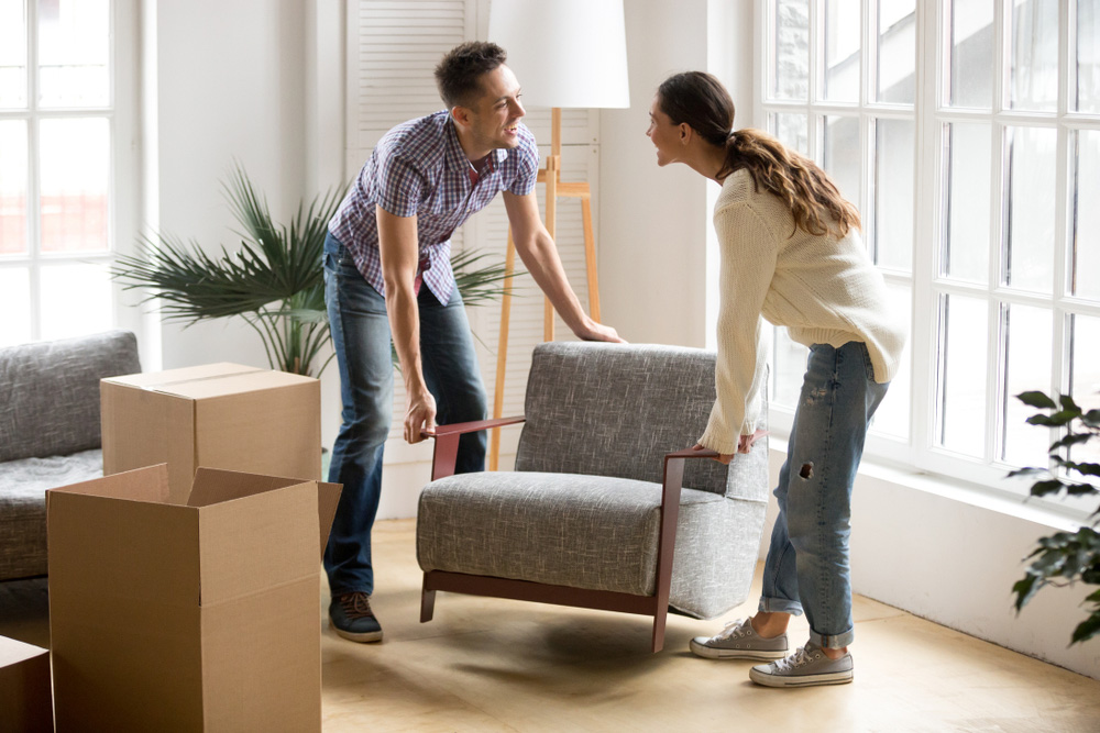 man and woman move a chair into their living room in their new home