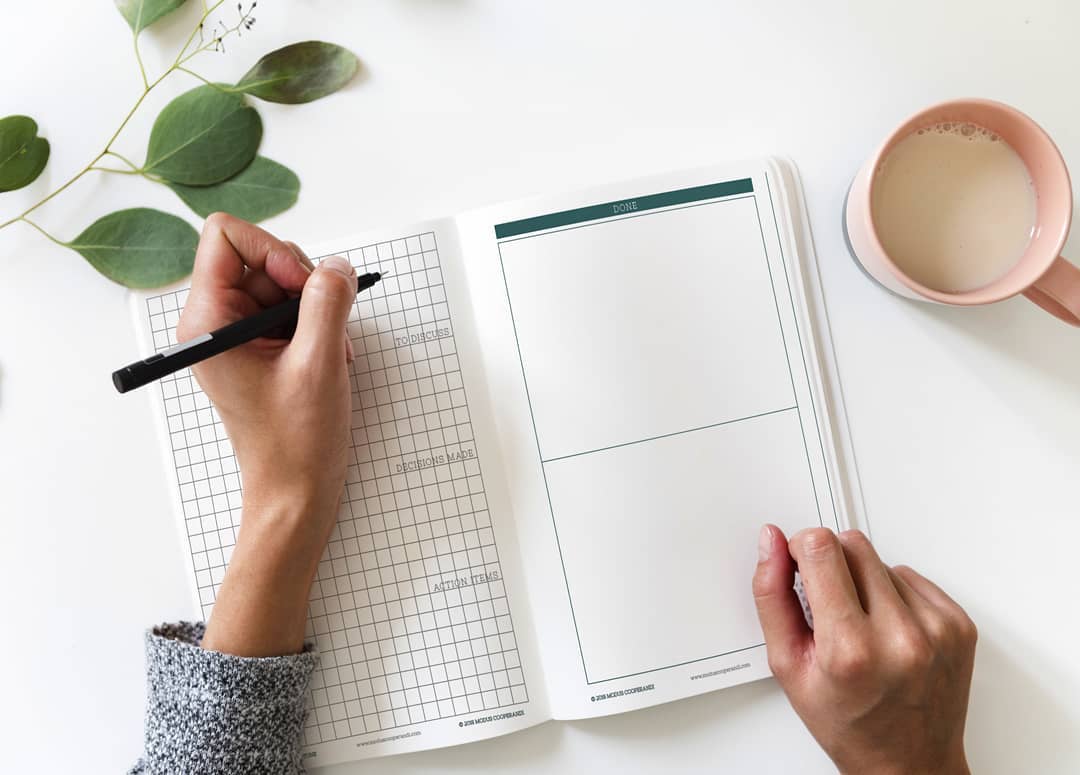 Woman Writing in Daily Planner. Photo by Instagram user @digitalcitymarketing