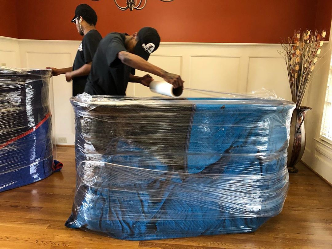 Man Wrapping a Large Dresser in Plastic Wrap for Moving. Photo by Instagram user @wolfpackmovers
