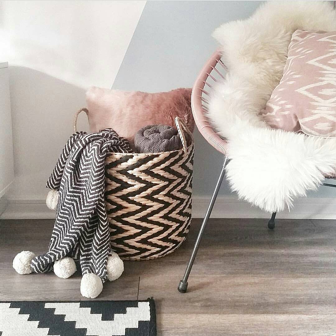 Cute storage basket with blankets and throw pillows next to chair. Photo by Instagram user @caffeineandcacti