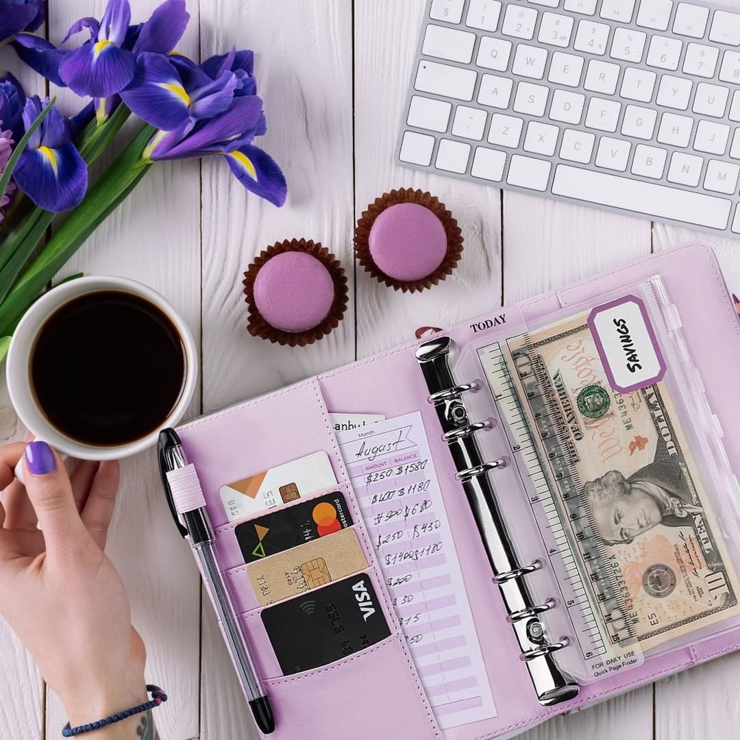 purple budgeting planner with save envelopes, coffee, and debit cards. Photo via Instagram user @twcpersonalbudgeting