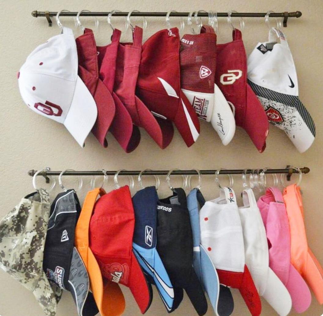 Baseball hats on shower curtain rings and metal rod. Photo by Instagram user @thingsinorder