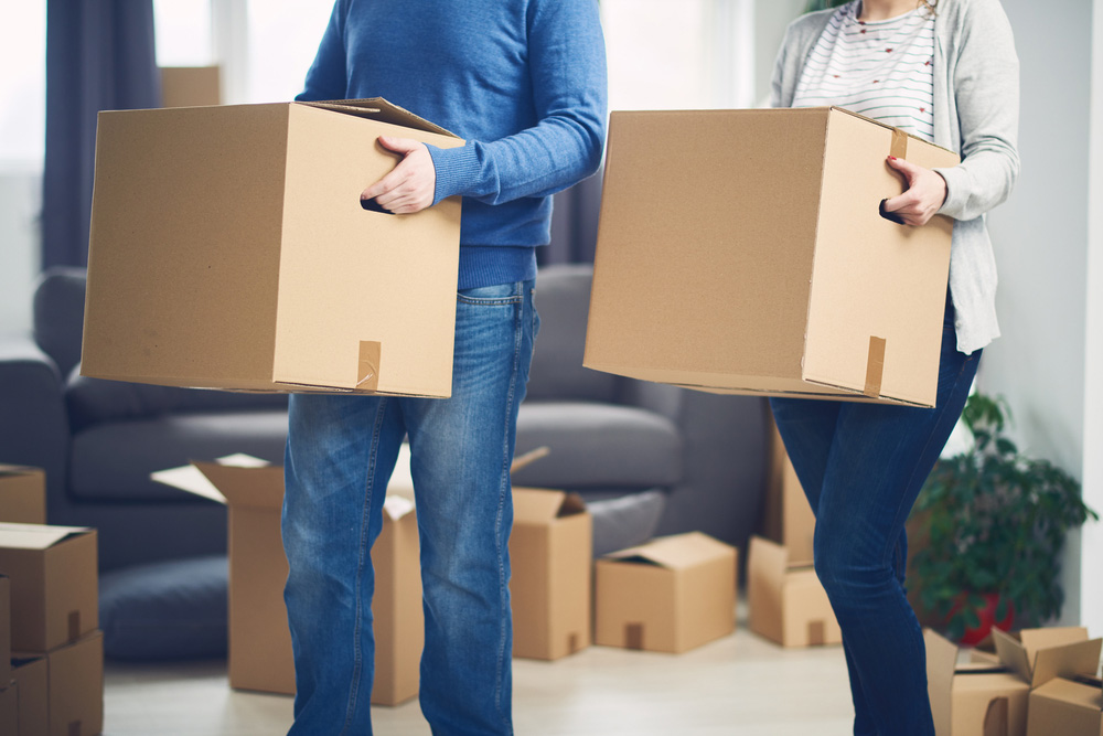 man and woman carry boxes into their new home