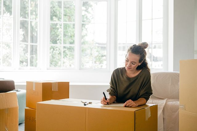 A woman labeling a moving box. Photo by Instagram user @jillianhugoandassociate