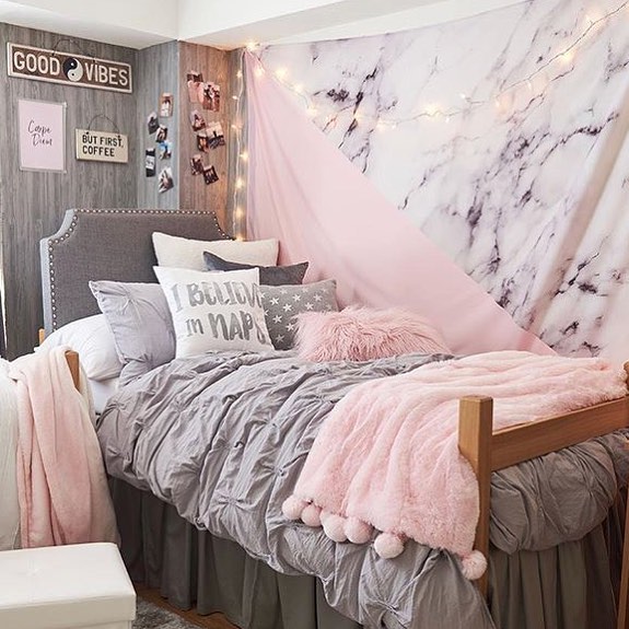 pink dorm room with throw pillows and blankets Photo via @tempaper_designs