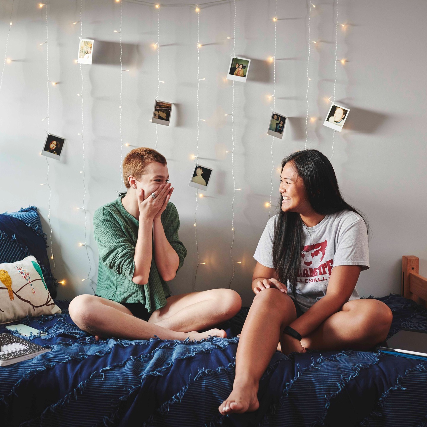 Two girls sitting on a dorm room bed smiling at each other. Photo by Instagram user @willamette_u