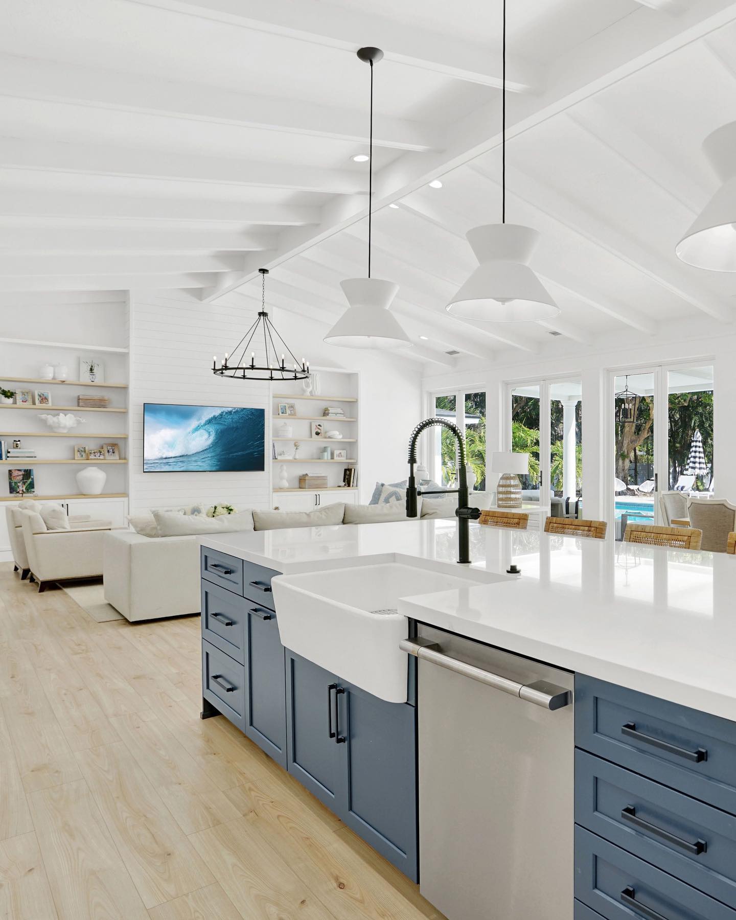 Side view of a kitchen island and living room with blue cabinets, modern kitchen, and high ceilings. 
