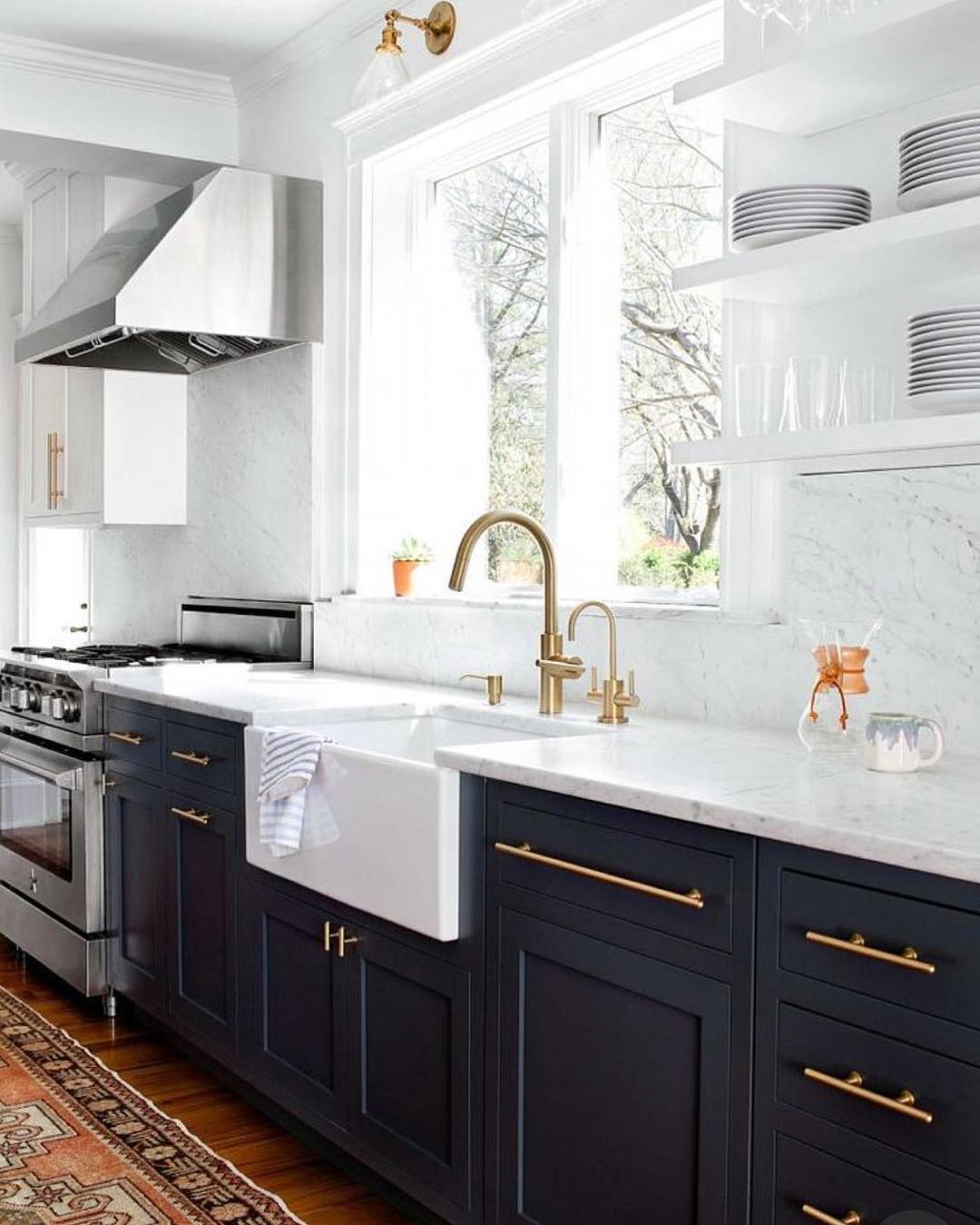 A kitchen countertop with charcoal gray cabinets and gold hardware for cabinet pulls and faucet is shown in picture. Photo by Instagram username @hadiyahlove