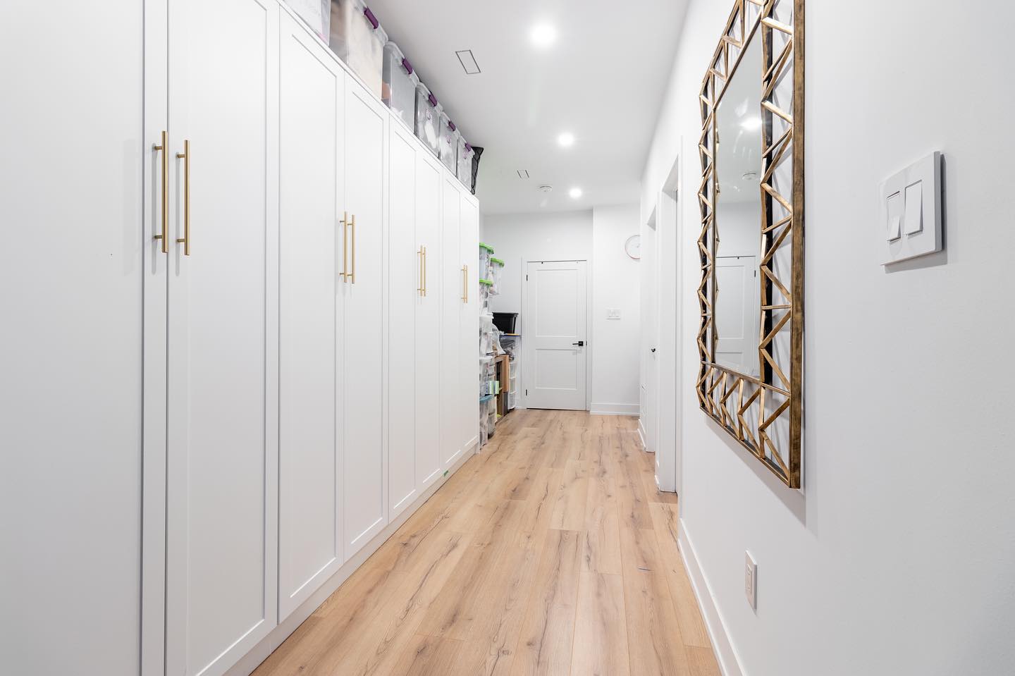 Basement storage area with storage cabinets, organized storage bins, and wood floors. Photo by Instagram user @furnishedinteriorsdevelopments