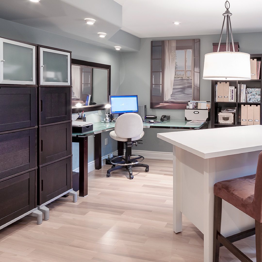 Basement home office with an L desk, a comfortable chair, and office storage cabinets. Photo by Instagram user @yasseininteriors.