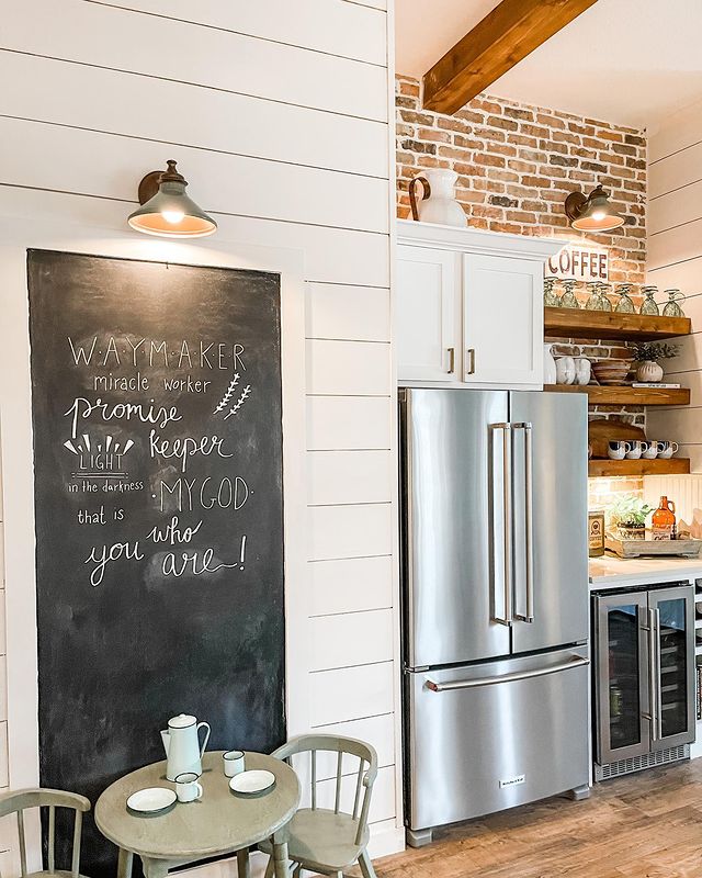 A kitchen with a chalkboard-painted wall next to a refrigerator is shown. Photo by Instagram username @judithkellarinteriors