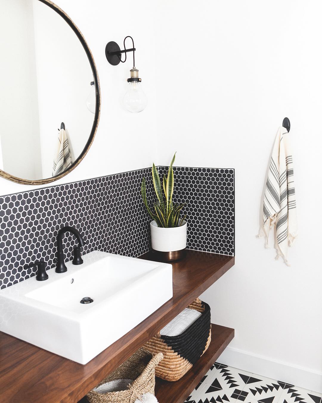 black tile backsplash with white sink and wooden counter in bathroom photo by Instagram user @theresidencybureau