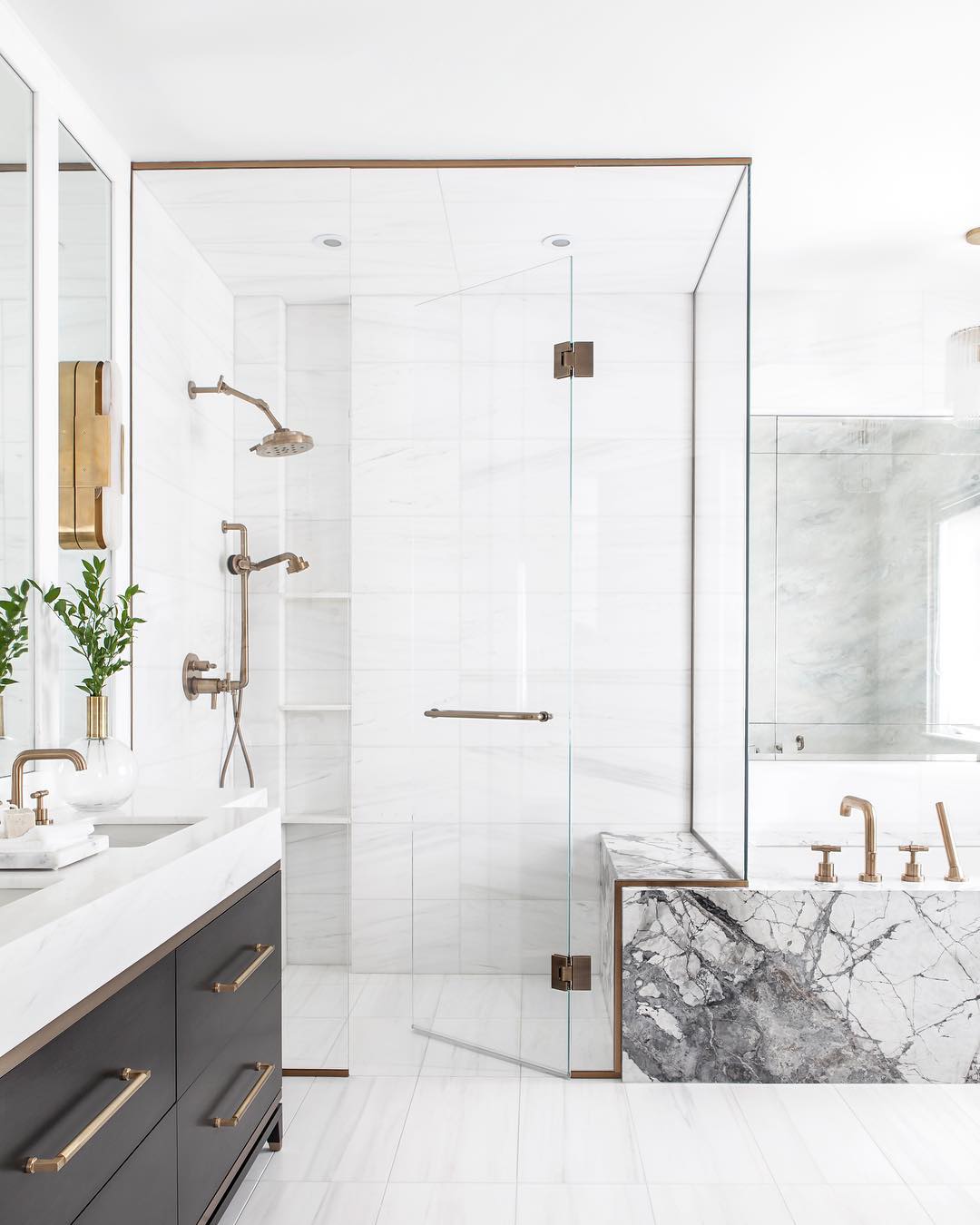 bathroom with white tile, glass shower walls, and gold hardware photo by Instagram user @kielyramosphoto