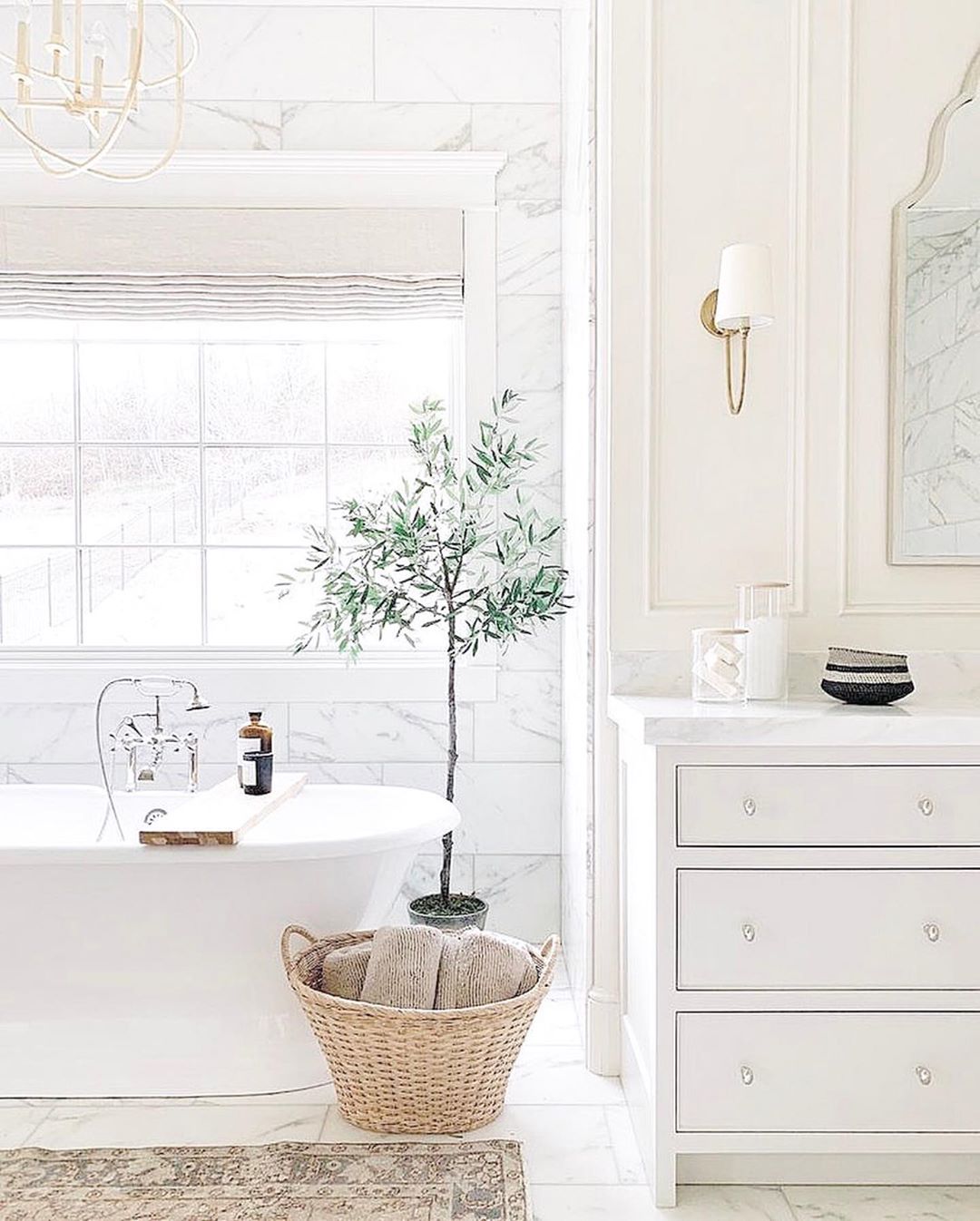 bathroom with lots of natural light next to soaking tub with small shrub in the bathroom photo by Instagram user @chandeliers.and.champagne
