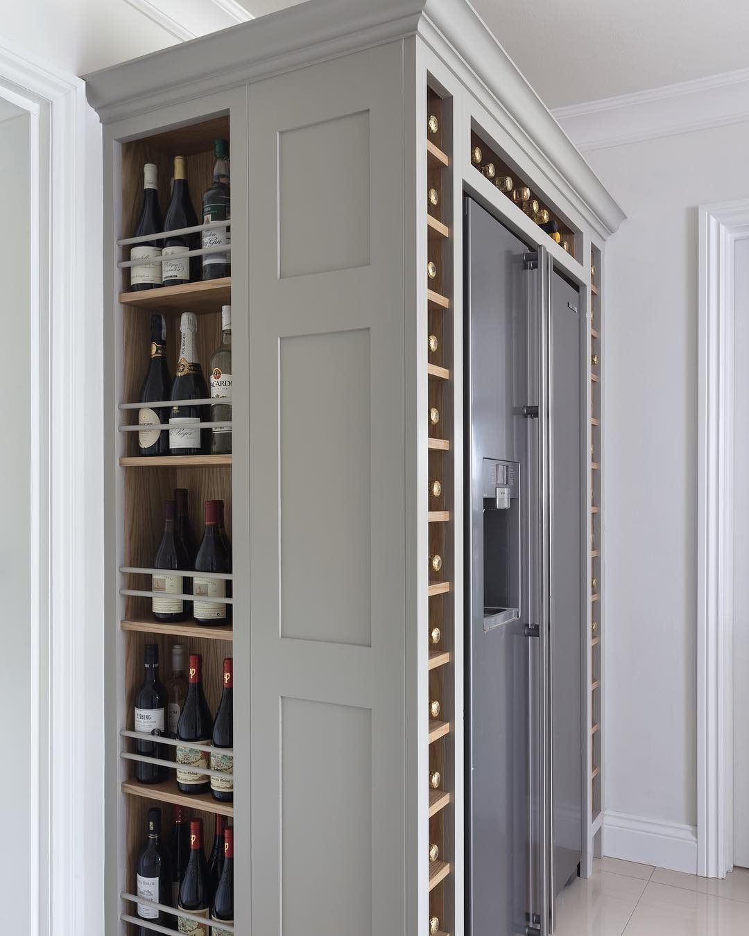 Custom-built wine storage around refrigerator. Photo by Instagram user @charliekinghamcabinetmakers
