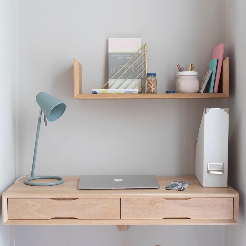 Floating desk with laptop and lamp.