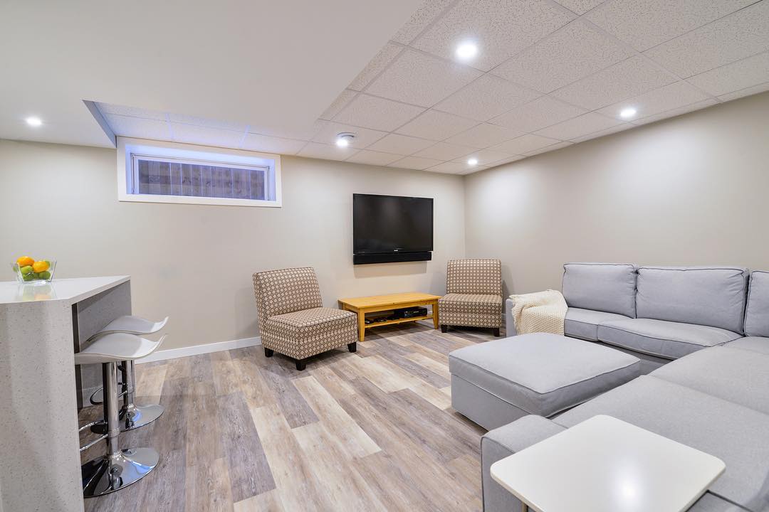 basement with couch and chairs with drop ceilings and recessed lighting photo by Instagram user @grindstonerenos