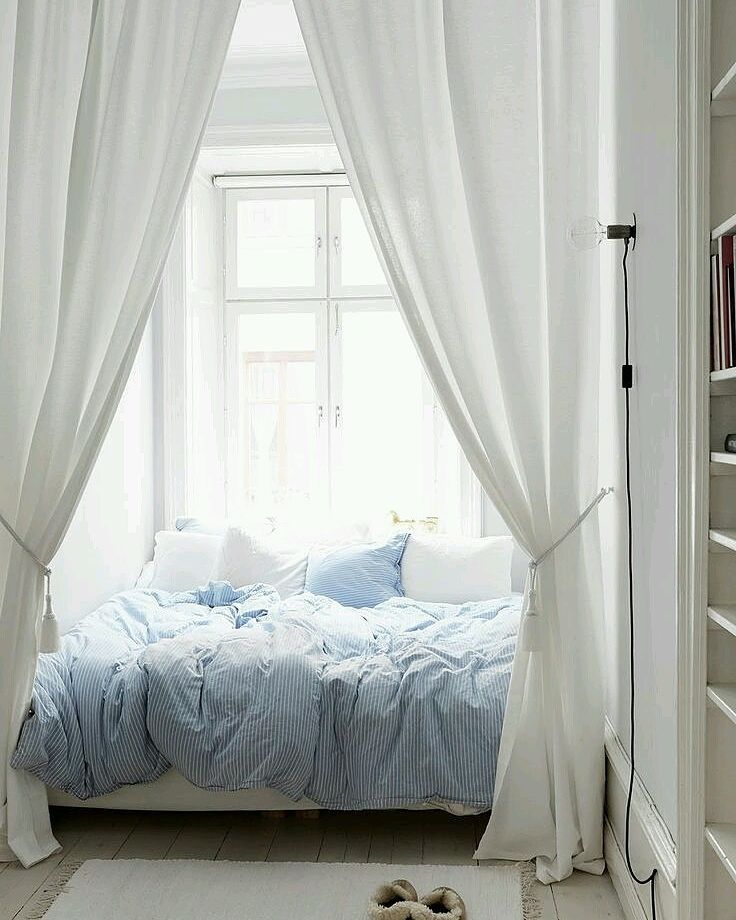 Bedroom with large white curtain surrounding bed.