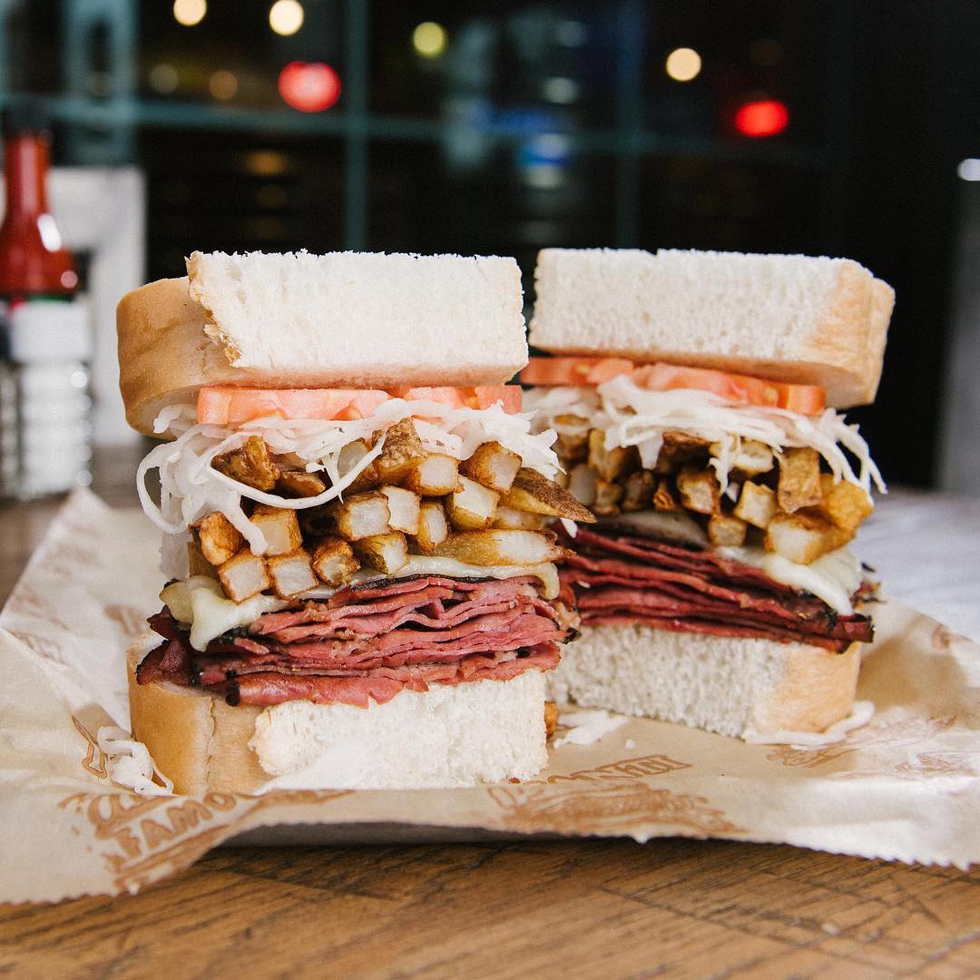 Pastrami sandwhich on white bread with french fries and tomatoes in the middle. Photo by Instagram user @primantibros