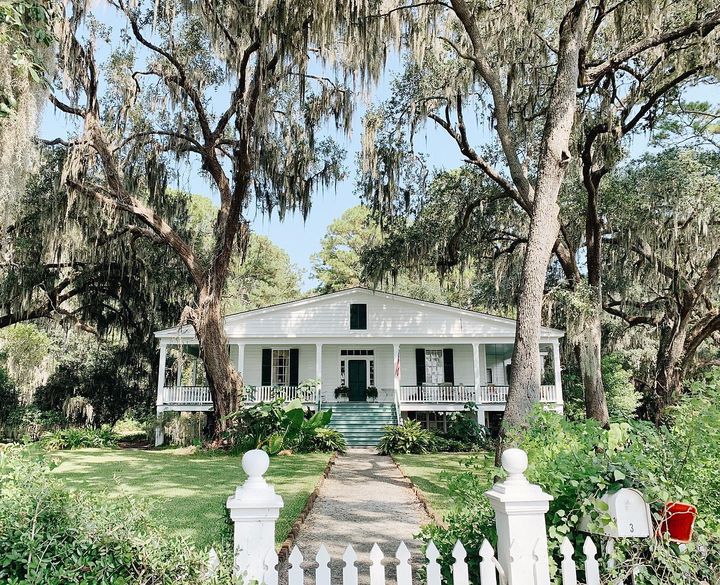 A white home with a picket fence and wrap-around porch in Isle of Hope, Georgia. Photo by Instagram user @ktmcgee.