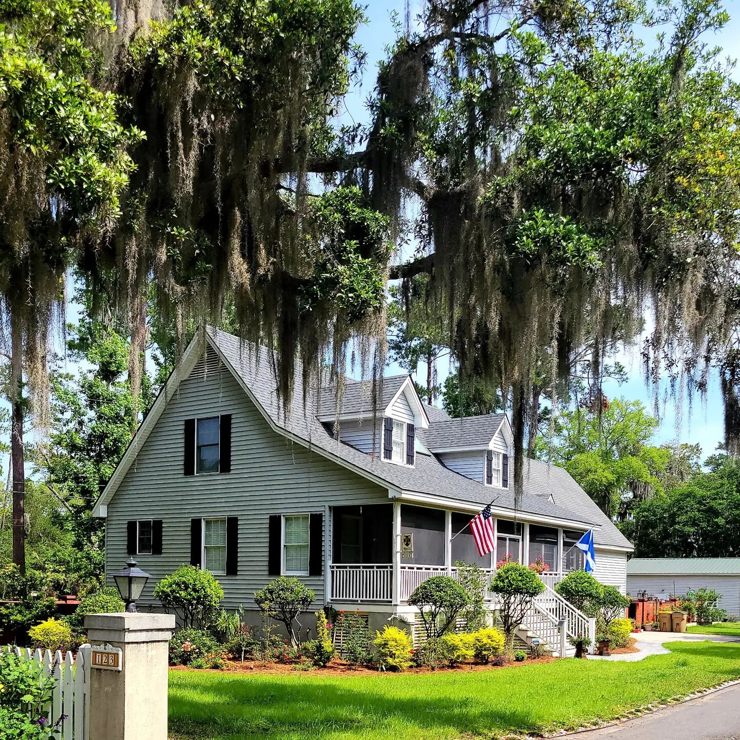 A gray Georgian home surrounded by trees covered in hanging Spanish moss. Photo by Instagram user @edgerlyrobert.