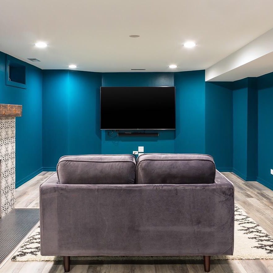 Basement Painted with Bright Blue Walls and a TV Hung on the Wall. Photo by Instagram user @magdainteriors