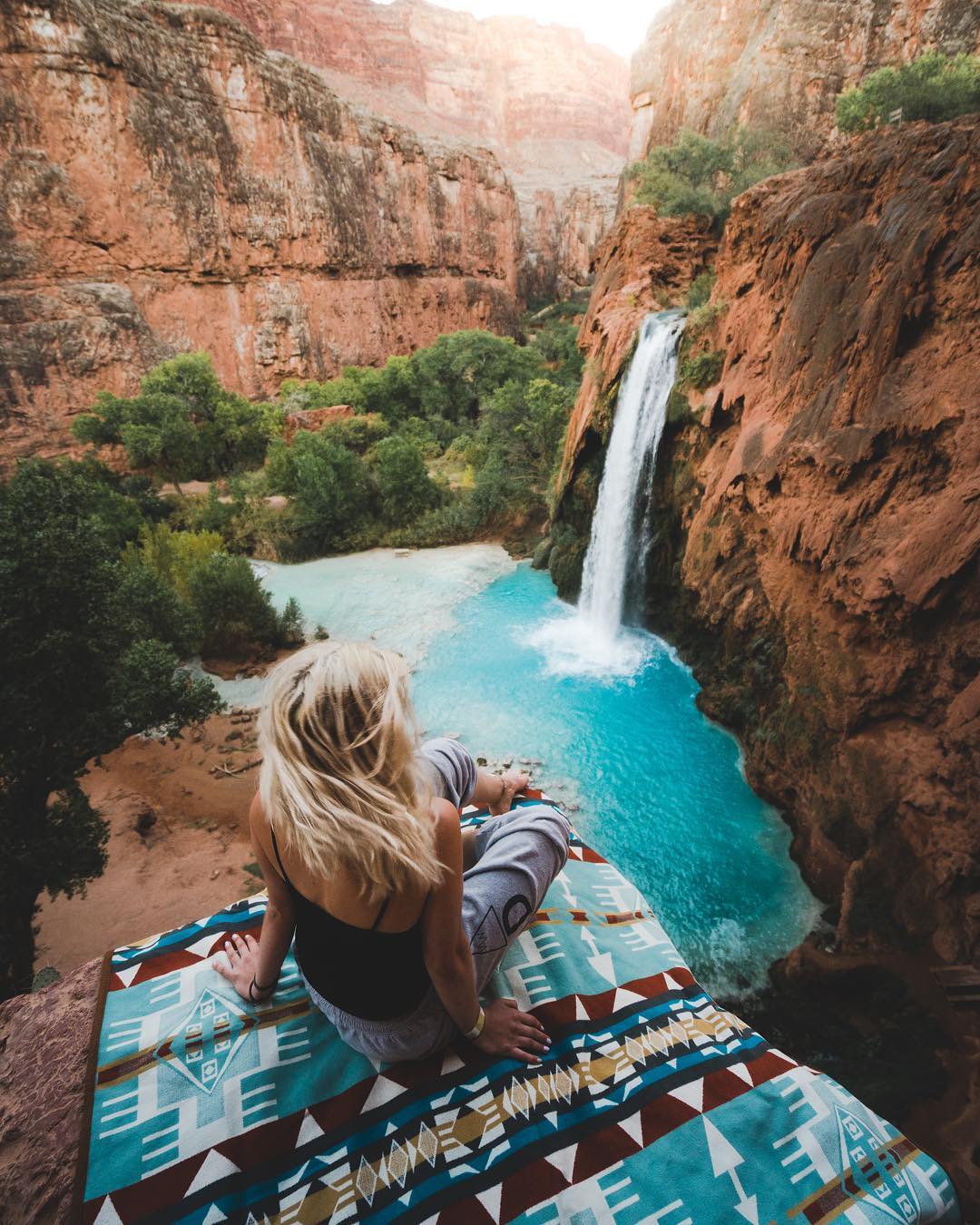 Woman sitting on cliff in Havasupai. Photo by Instagram user @braybraywoowoo