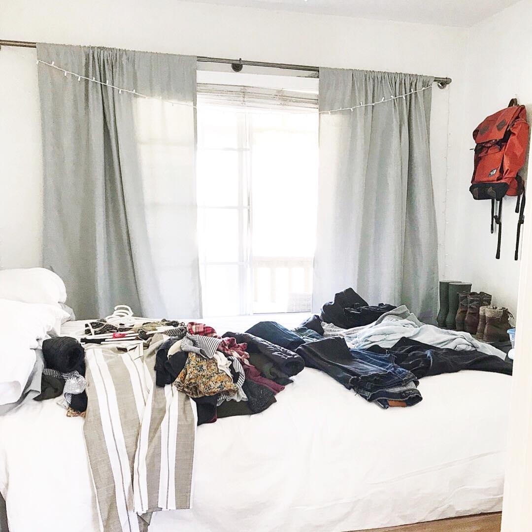 Bed covered in clothing. Photo by Instagram user @thelaminimalist