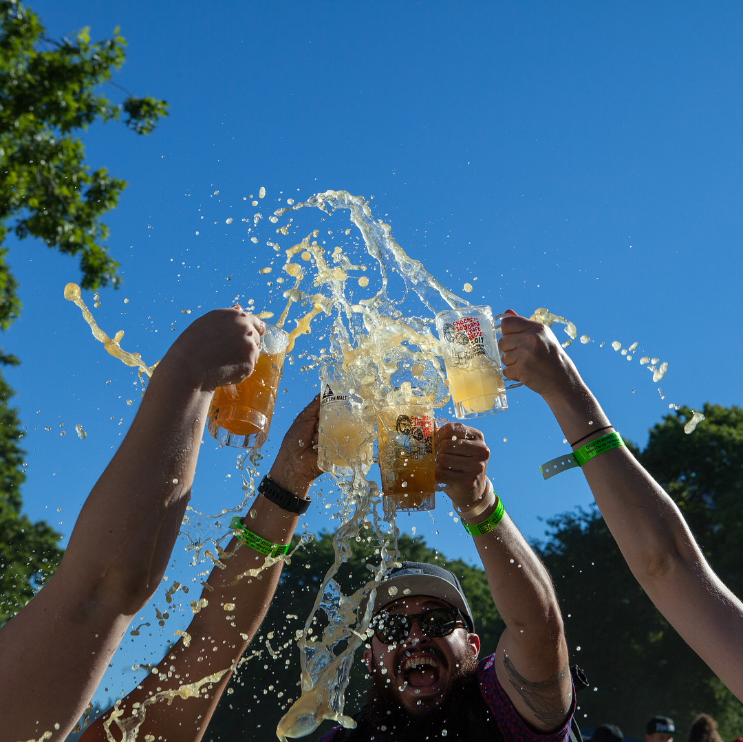 Beer splashing out of steins after enthusastic cheers by a group of people Photo by @oregonbrewfest