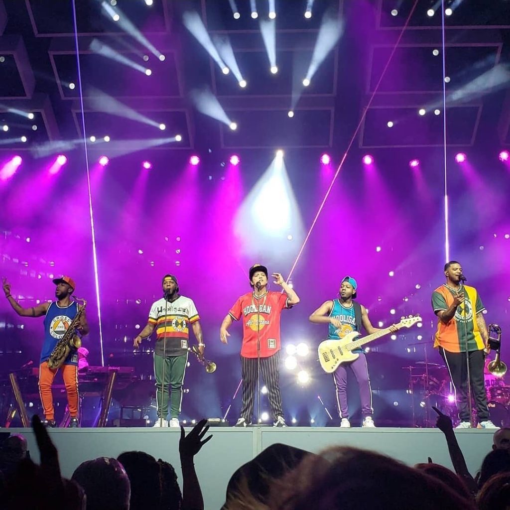 Bruno Mars and 4 instrumentalists and singers perform on a purple stage in front of cheering fans. Photo via Instagram user @marssars75