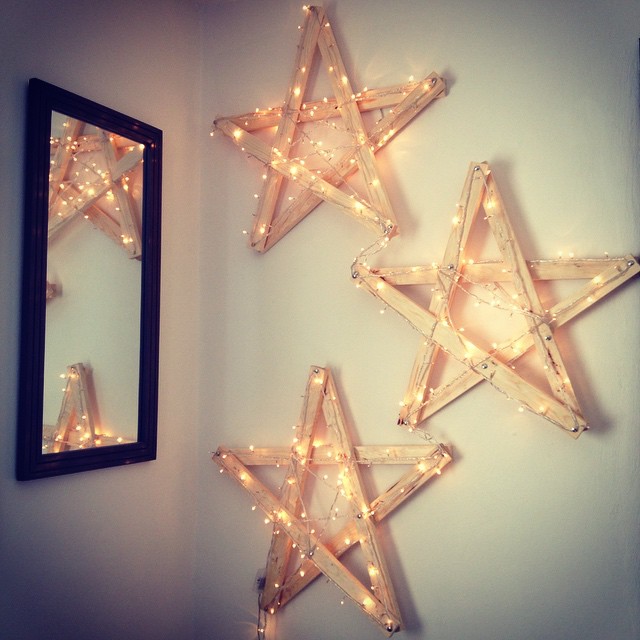 Homemade Wooden Stars Wrapped in Christmas Lights Hanging on Wall in Home. Photo by Instagram user @joelsp84