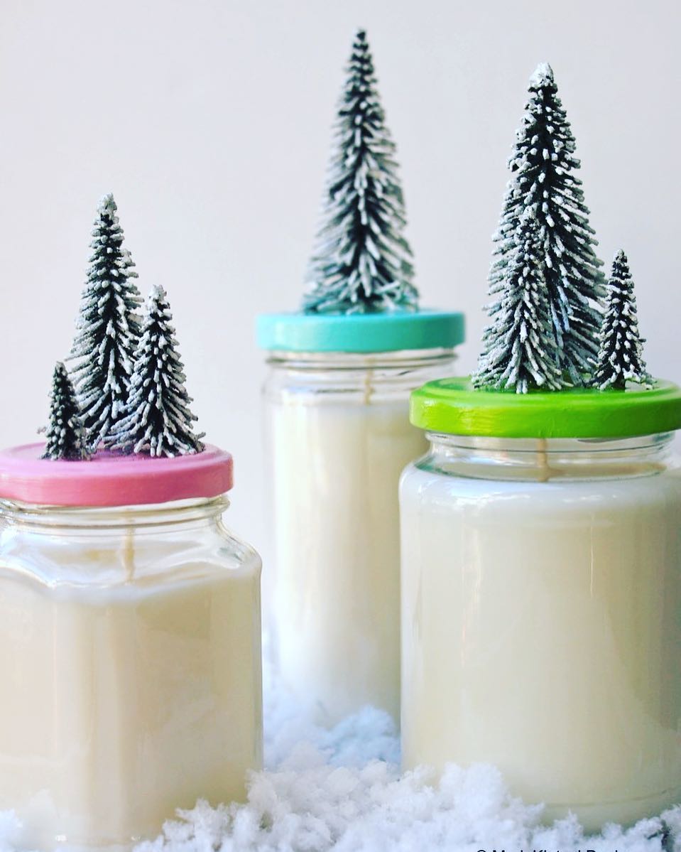 Homemade Candles in Old Jars Topped with Small Christmas Trees. Photo by Instagram user @markkintzeldesign