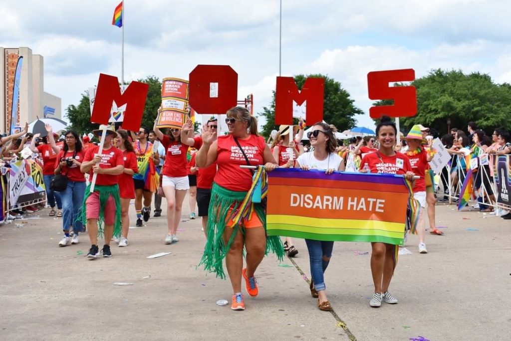 A group of women walk in the Dallas Pride Parade holding signs that say "Moms" and "Disarm Hate". Photo via Instagram user @dallasprideofficial