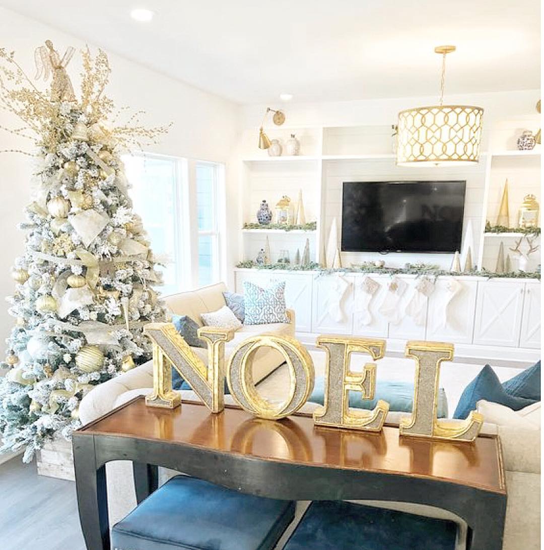 Couches and Christmas Tree in Living Room with NOEL Letters on Table. Photo by Instagram user @caliber_homes
