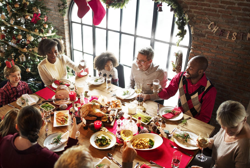 family and friends sit around a table and cheers before their holiday meal