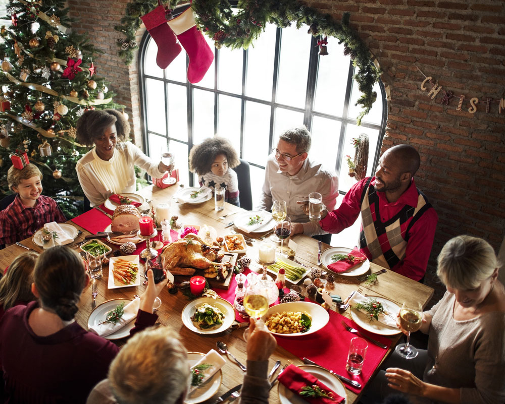 family and friends sit around a table and cheers before their holiday meal