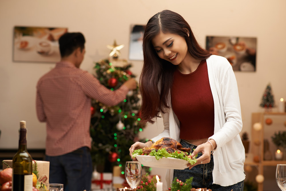 Woman preparing Christmas dinner table.