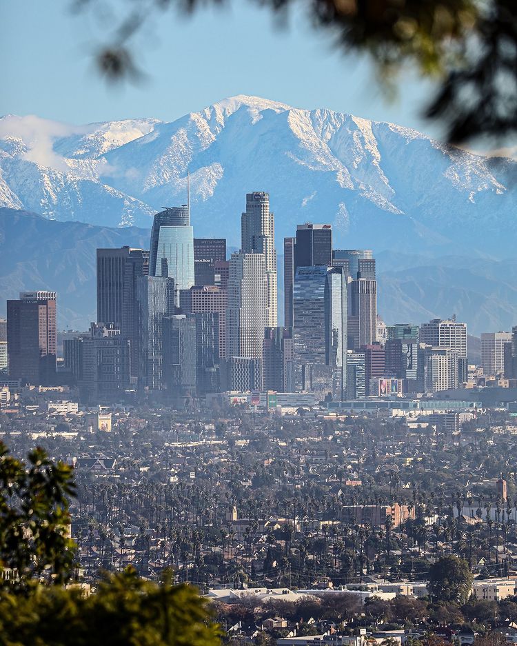 Los Angeles skyline with skyscraper buildings in front of snowcapped mountains. Photo by Instagram user @donnys.photography