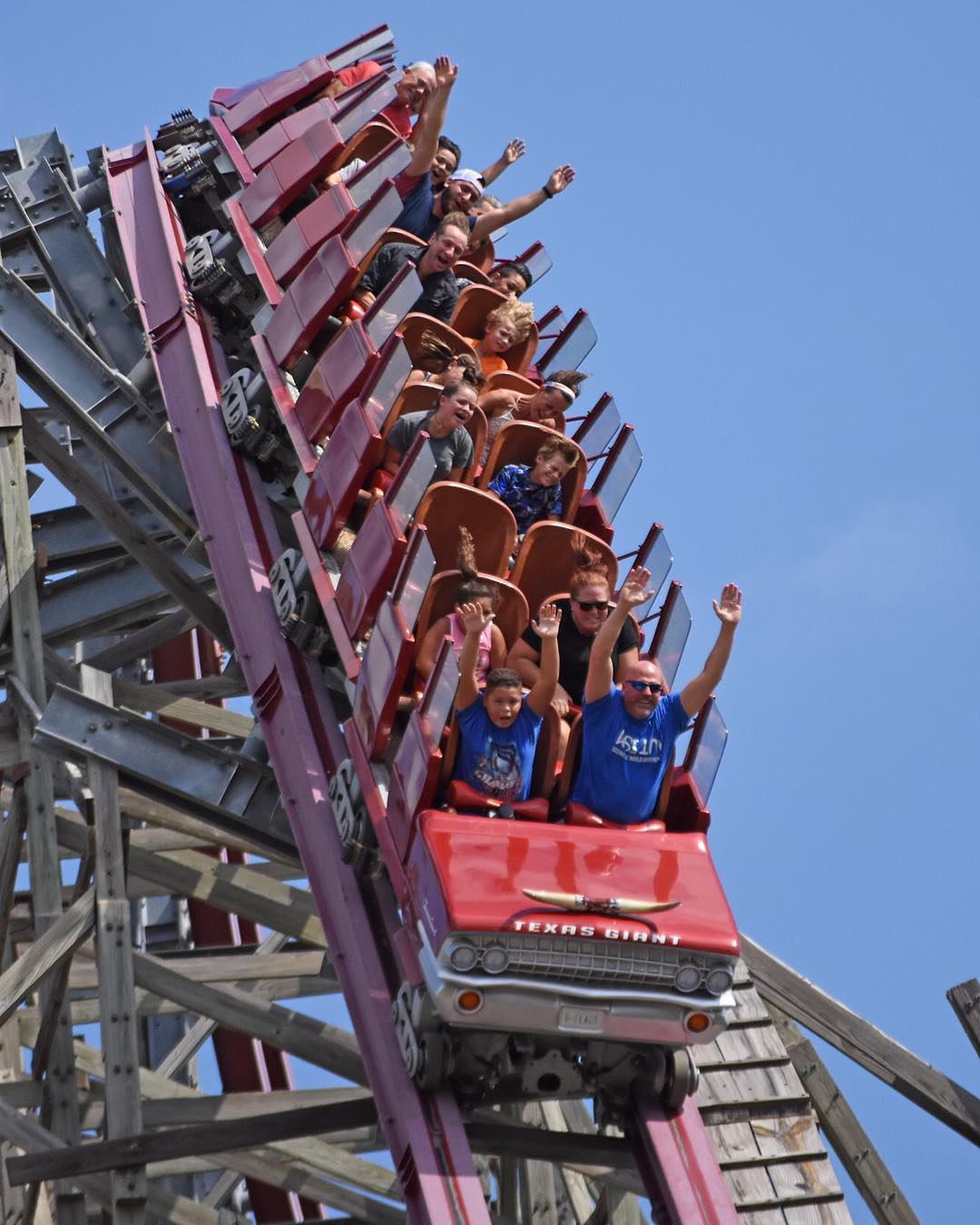 Riders hold up their arms on a rollercoaster Photo by Instagram user @sixflagsovertexas