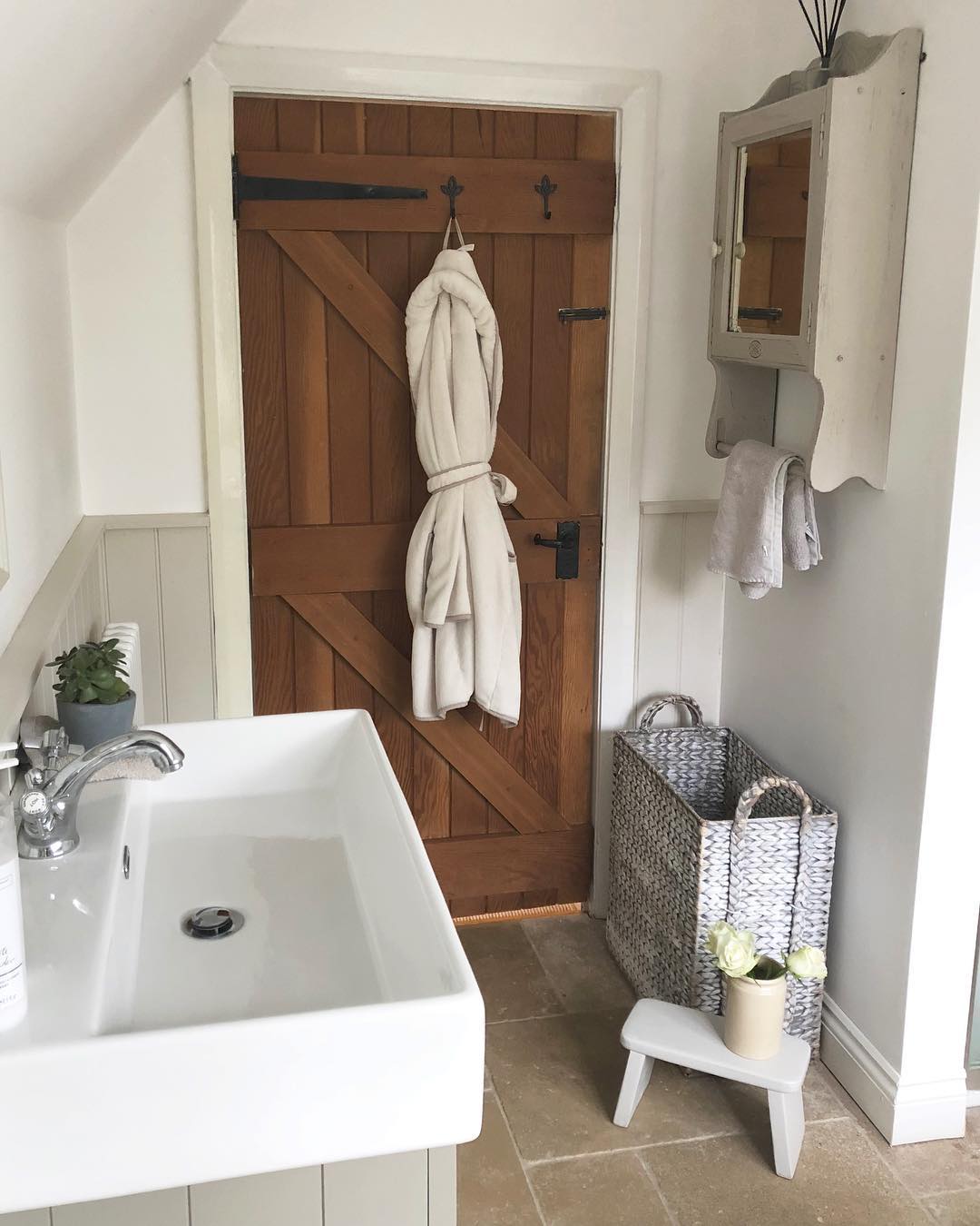 Farmhouse-style bathroom with wooden barn door. Photo by Instagram user from_coast_to_country_home