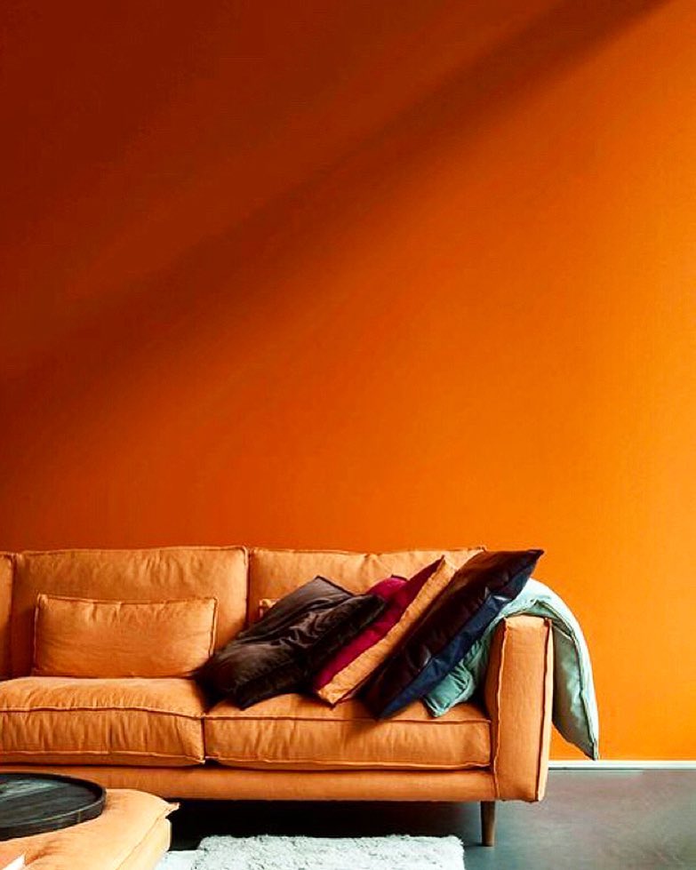 Living room with orange accent wall. Photo by Instagram user @marieburgos.design