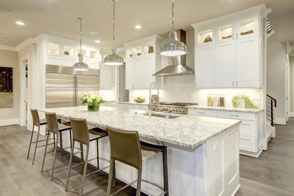 Feng shui kitchen design featuring white cabinets with lighting and large island.
