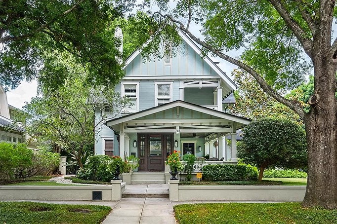 Gray Craftsman-style house with white trim and window and brown door beside green landscaping and lawn in Hyde Park Tampa neighborhood. Photo by Instagram user @kseniya.tamparealtor