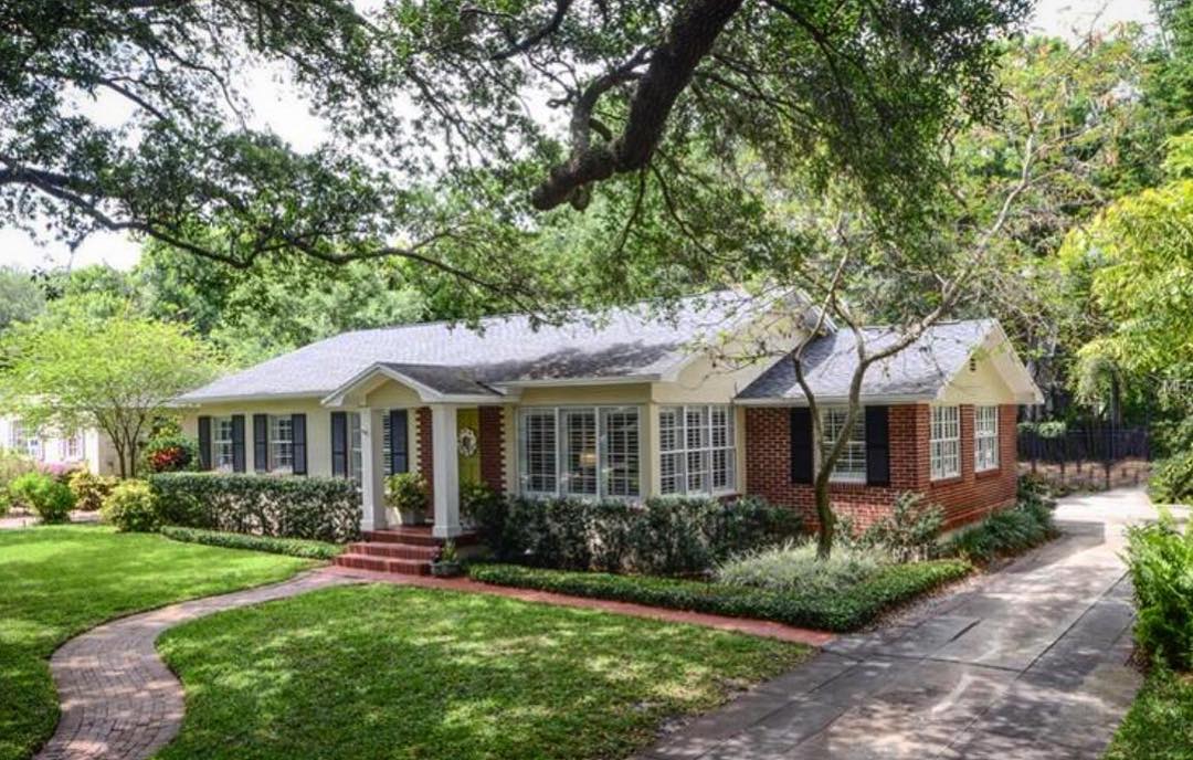 Traditional ranch style home with red brick and dark shutters and white window trim. Photo by Instagram user @thewertzgroup