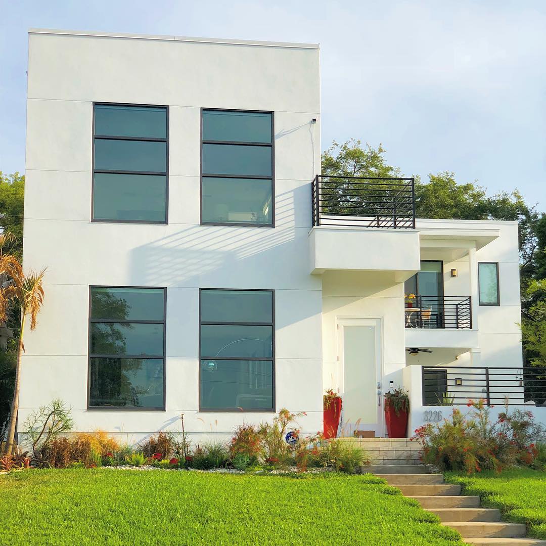 Very modern two story white home with black iron railings at each baloncy. Photo by Instagram user @yourtampaexpert