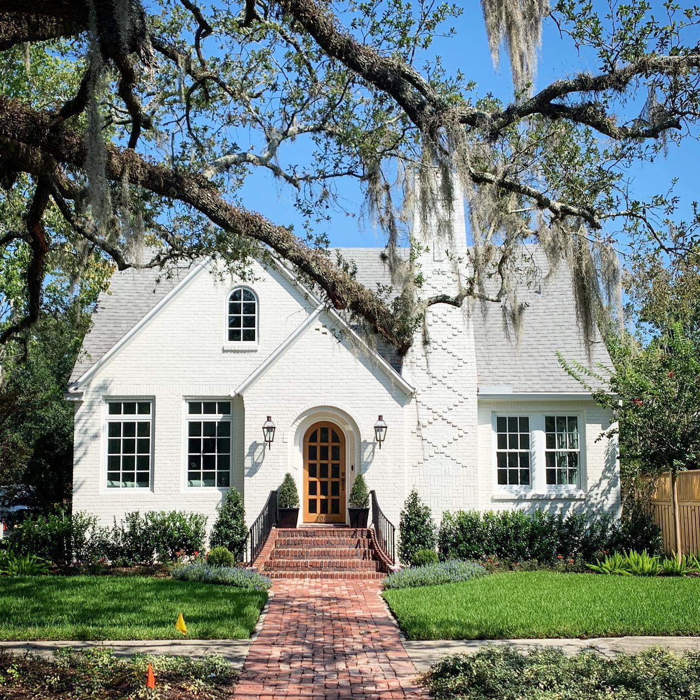 A white brick cottage with a stone path leading to the front door in San Marco Square, Jacksonville. Photo by Instagram user @jonessweethomes.