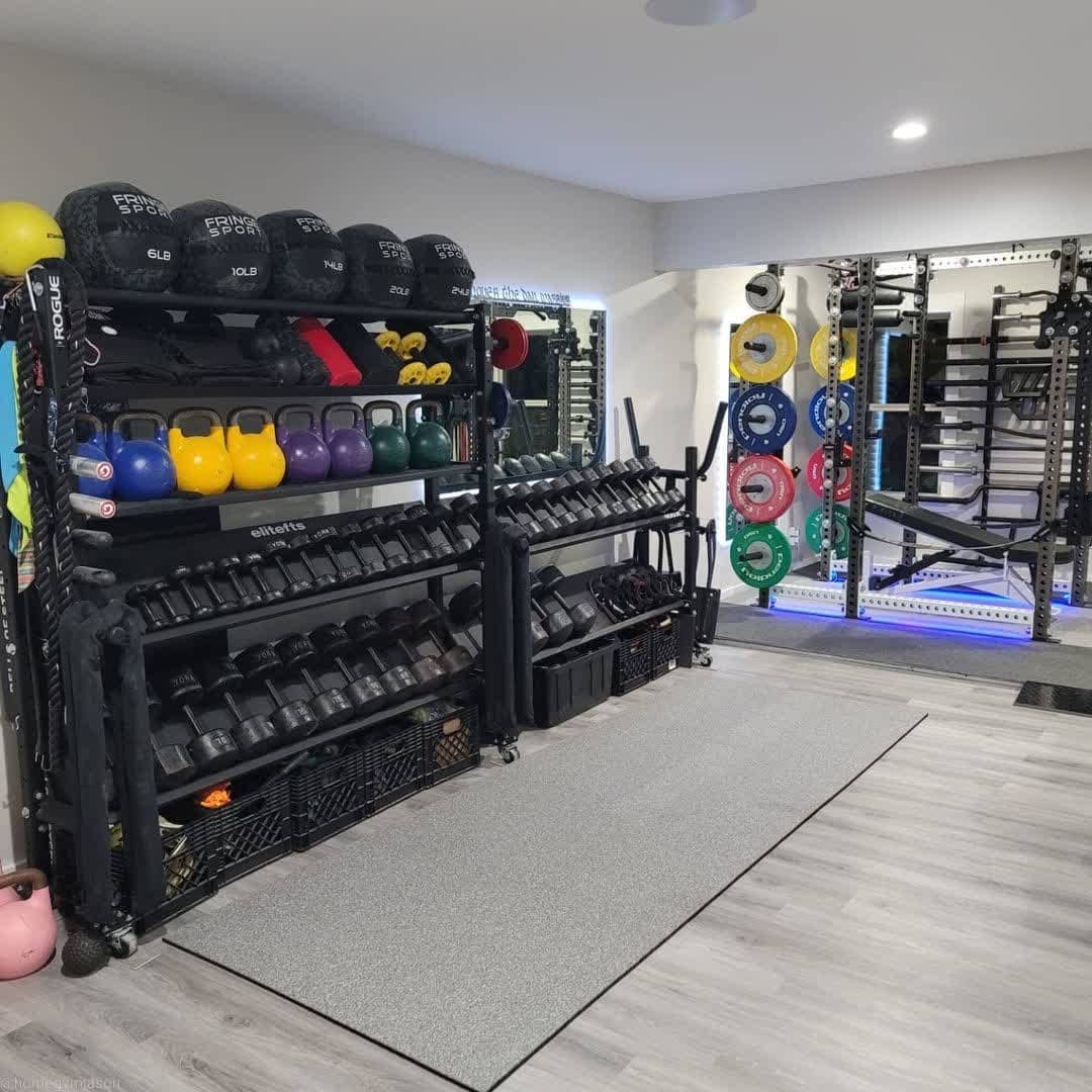 Big home gym with different-colored kettlebells and a large mirror against a wall. Photo by instagram user @garagegymexperiment