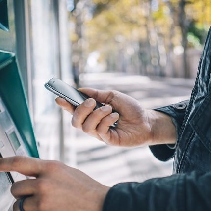 Man Looking at His Phone While Using a Bank ATM. Photo by Instagram user @atmserviusa