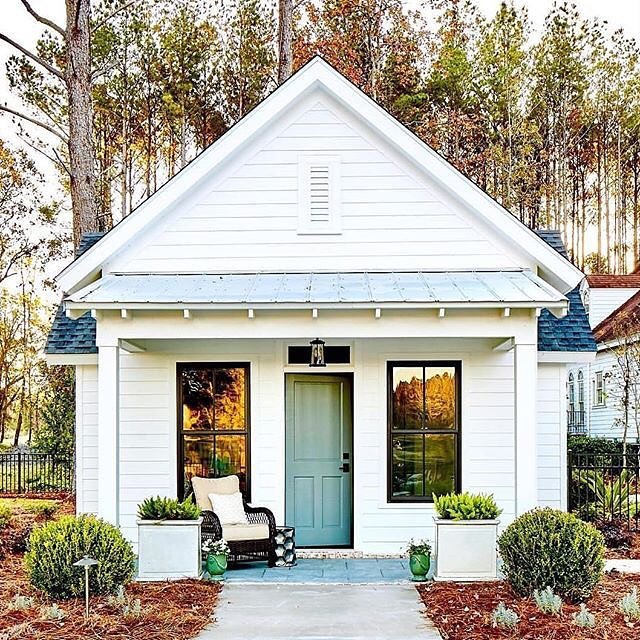 White Cottage with Blue Front Door and Rocking Chair on Front Porch. Photo by Instagram user @lyndsy.wojtus.realtor