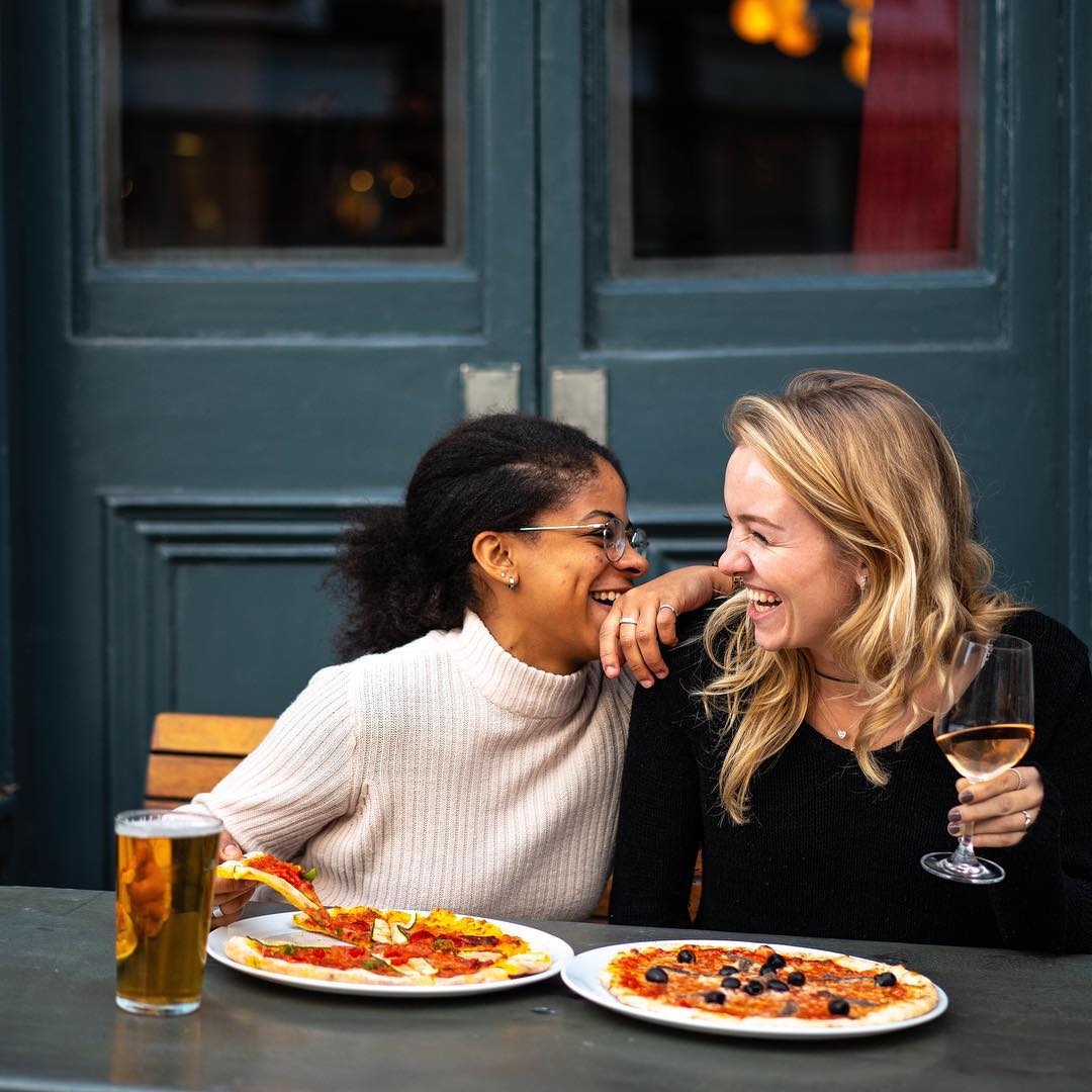 Two Women Eating Pizza on a Patio During a Date. Photo by Instagram user @thebelrose_pub